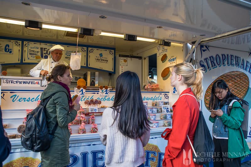 Three people standing at a stroppwaffle stand