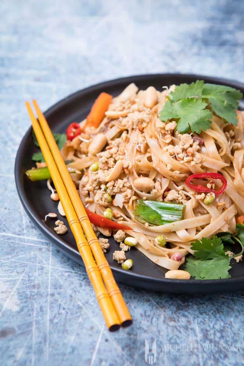 Two chopsticks on a plate of vegan pad thai 