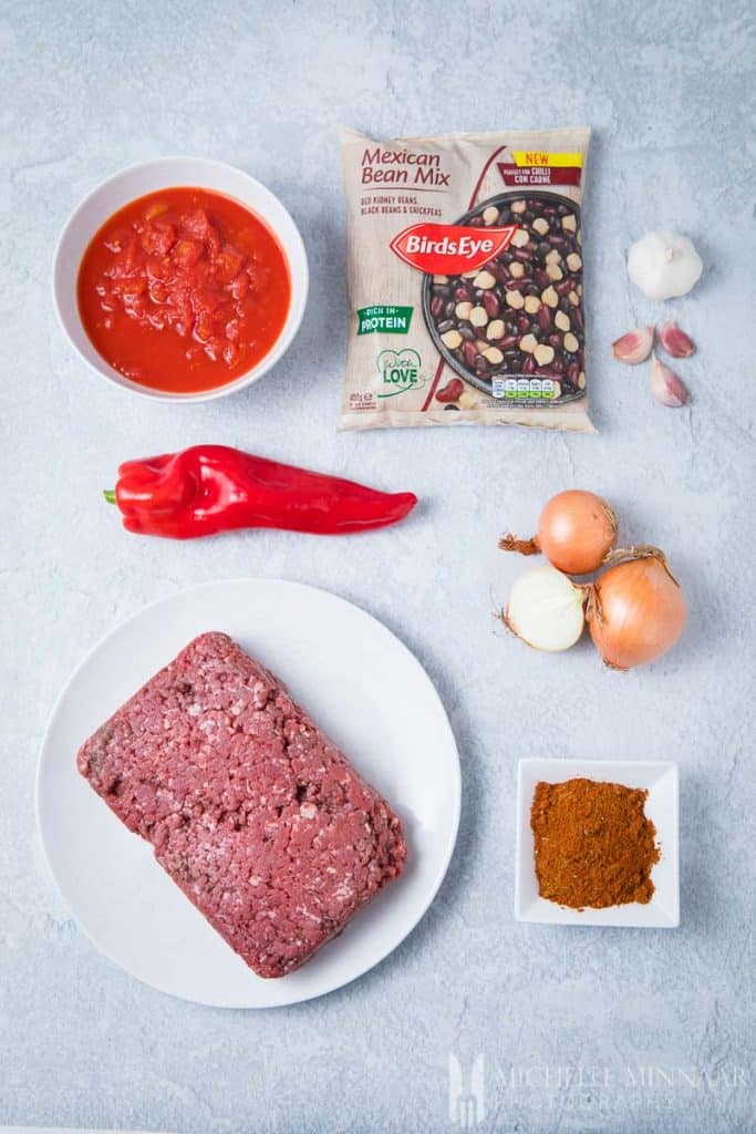 Ingredients to make venison chili : raw venison, red pepper, onion, chili powder, mexican bean mix