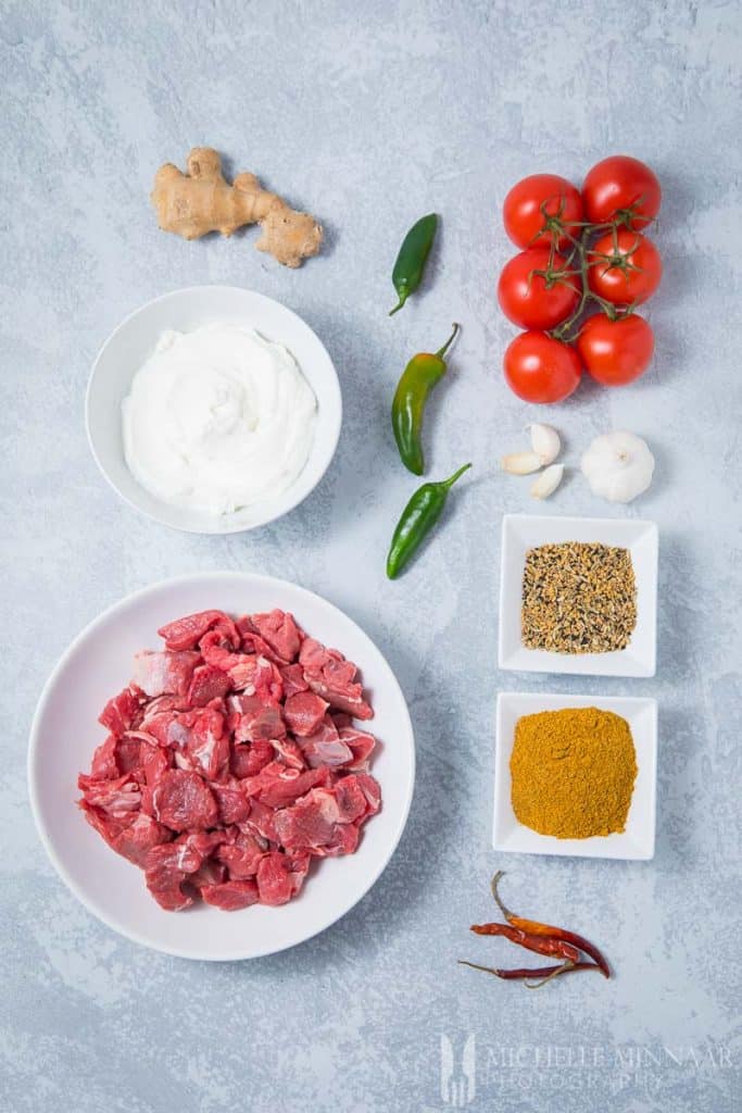 Ingrediënten om achar gosht te maken: tomaten, rundvlees, kruiden, paprika's, gember