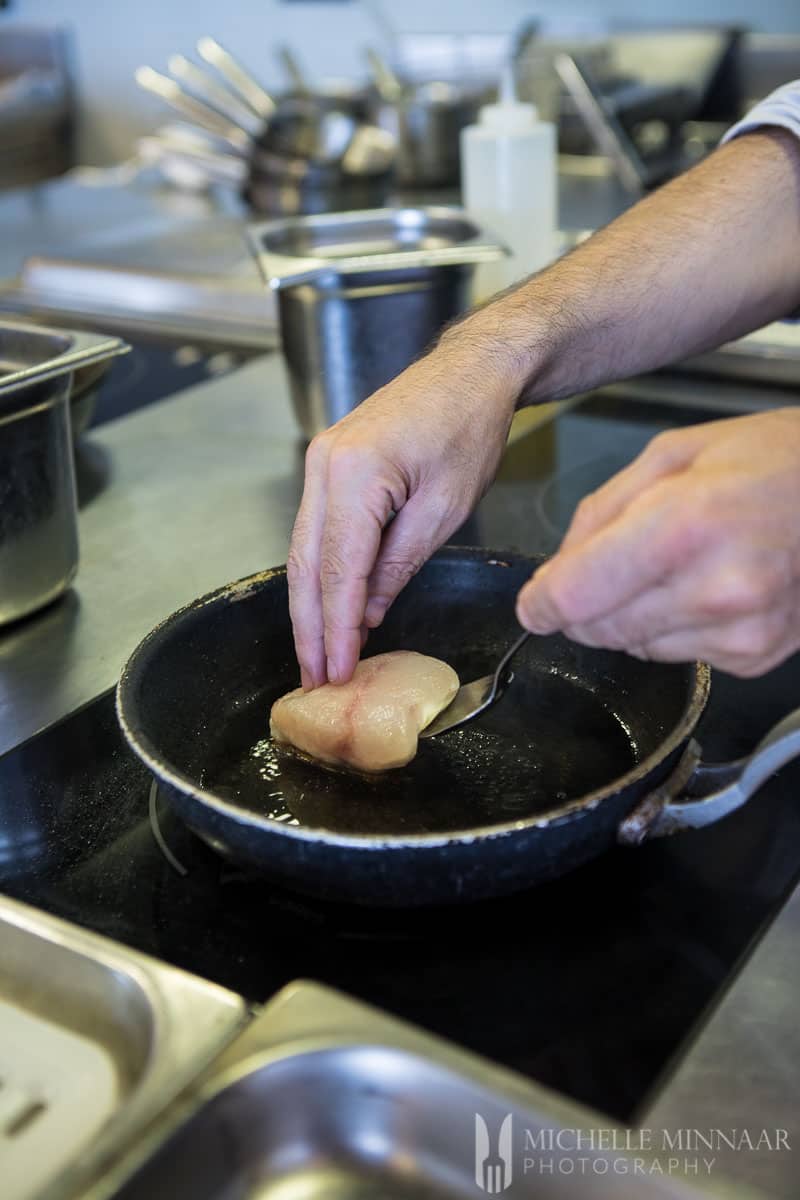 A man cooking a piece of grilled wreckfish