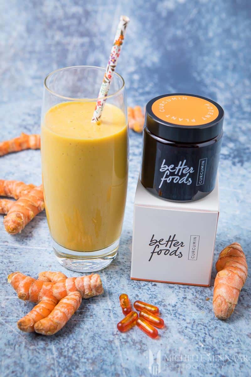 A yellow turmeric smoothie and a jar of better foods on top of a box