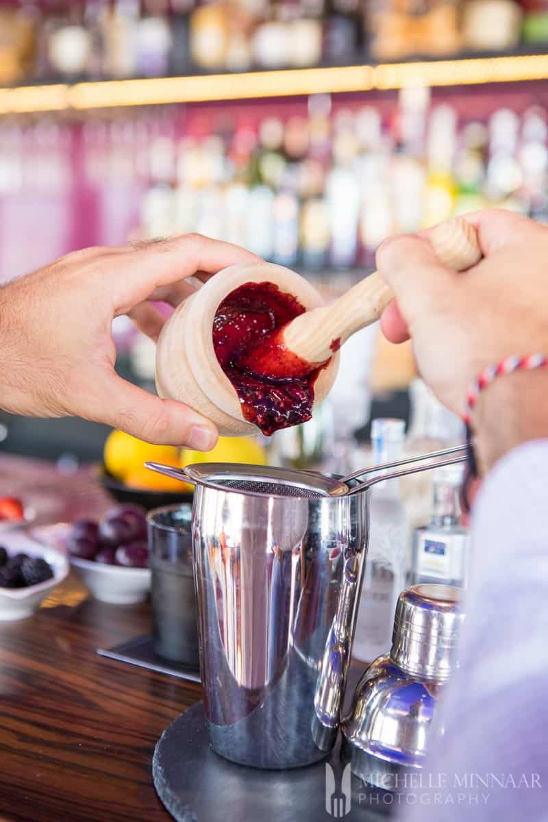 Muddled fruit being poured into a mixer