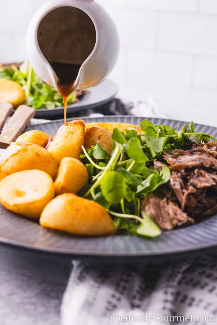 slow roast lamb shoulder served with potatoes and greens.