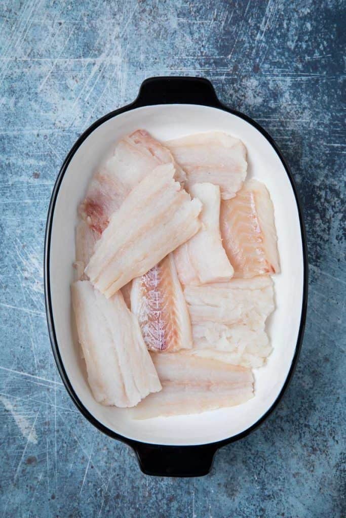 Raw cod fillets in a white pan