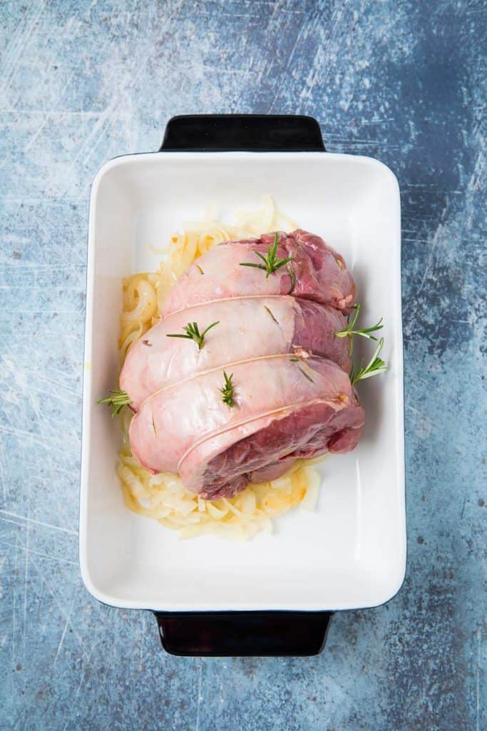 A raw roast of venison in a white dish 