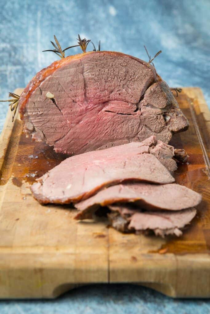 A large piece of roast venison on a cutting board cut in half