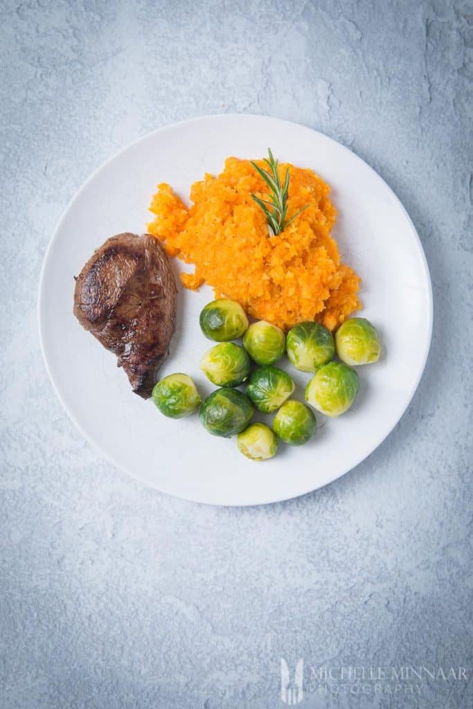 A plate with venison, brussel sprouts and orange mash 