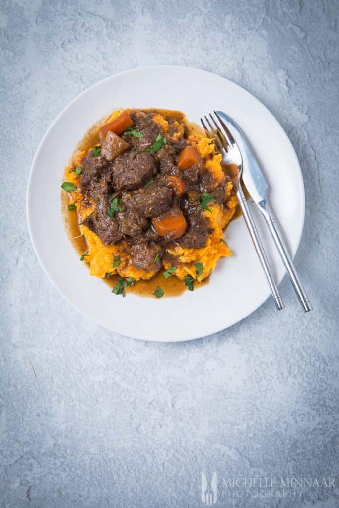 A plate of venison stew with a fork and knife