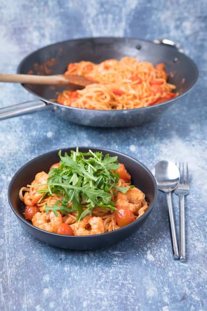 A skillet of pasta in a pan and a bowl of chilli prawn pasta
