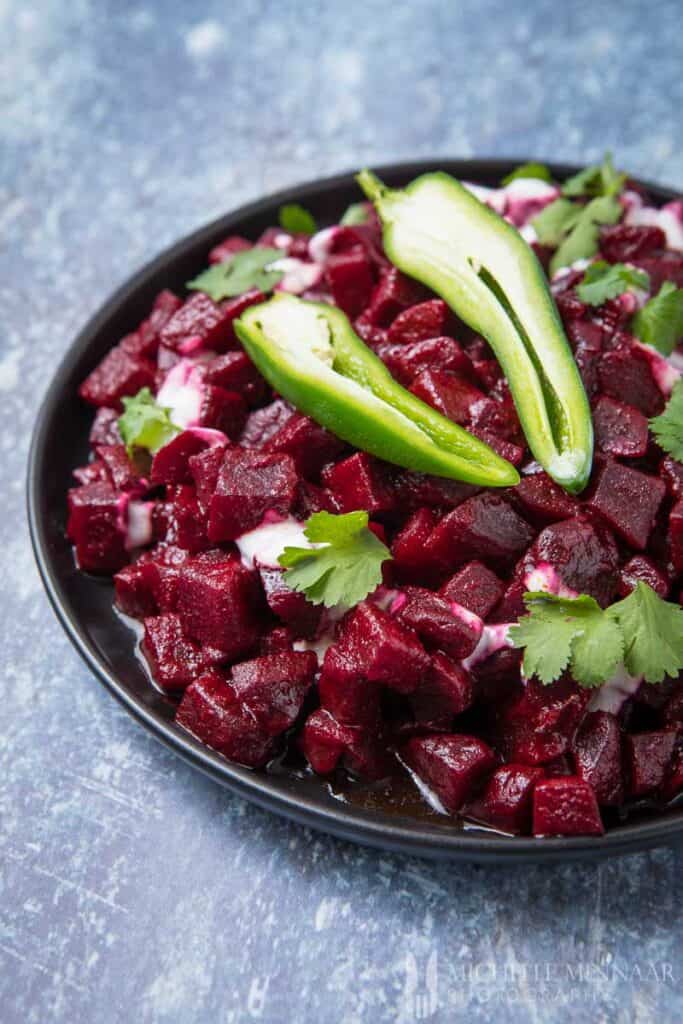 A bowl of Beetroot Curry with two peppers on top 