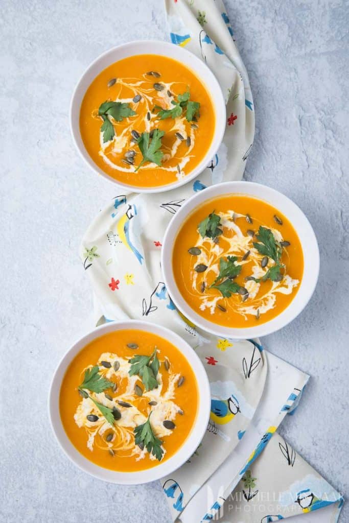 Two bowls of pumpkin and sweet potato soup