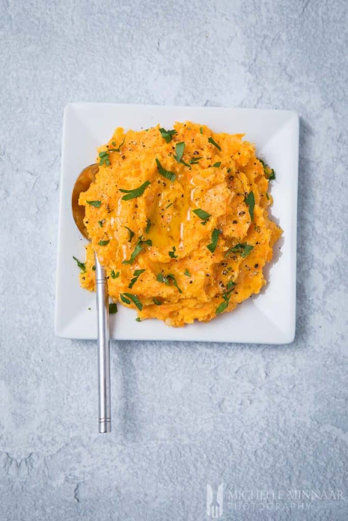 A plate of orange carrot and parsnip mash