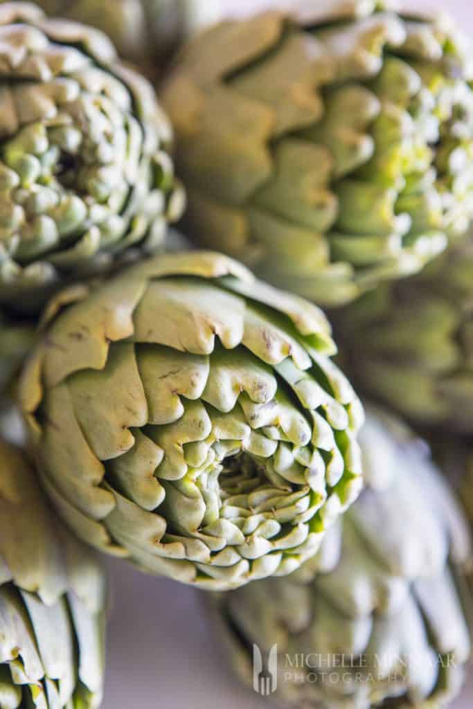 Three raw green artichokes