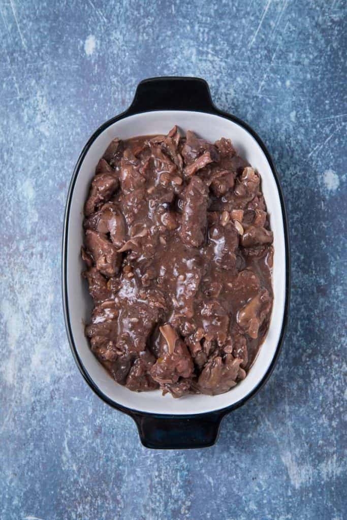 A pile of game meat covered in a brown sauce in a pan 