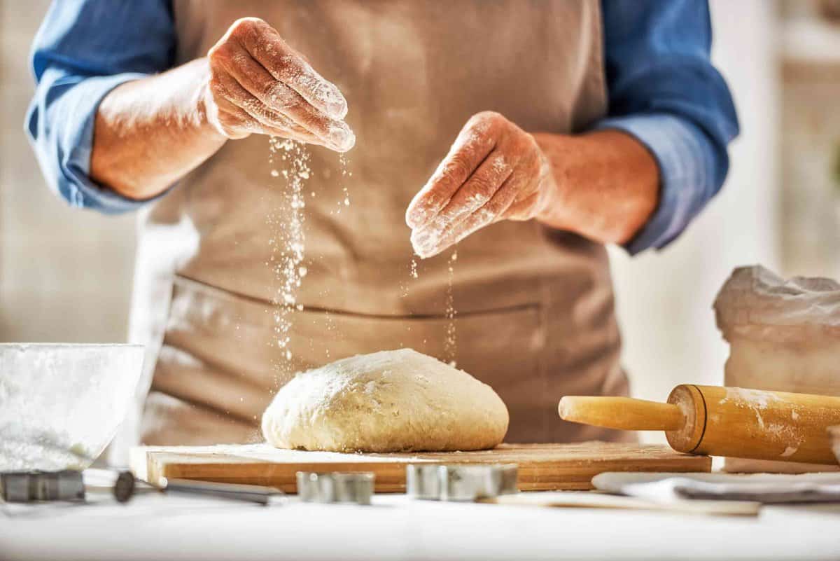 A man sprinkling flour on dough