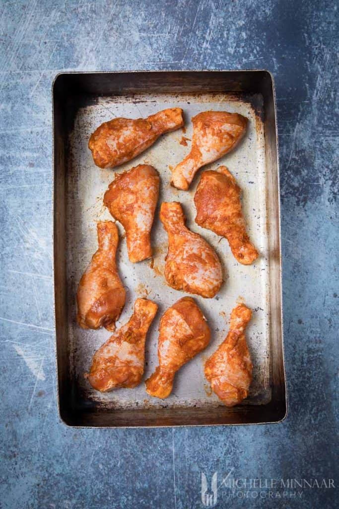 Raw Chicken Drumsticks on a pan with seasoning