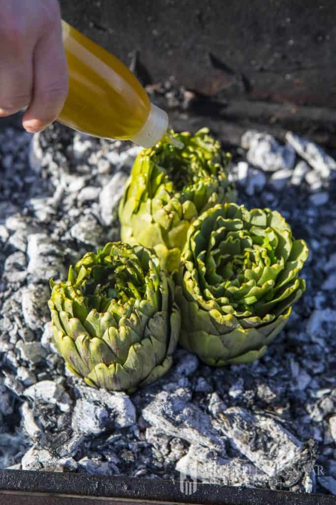 Oil being drizzled showing you how to cook artichokes