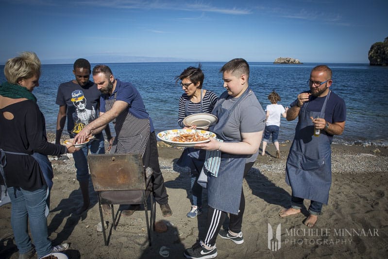 A group of people on a beach getting food 