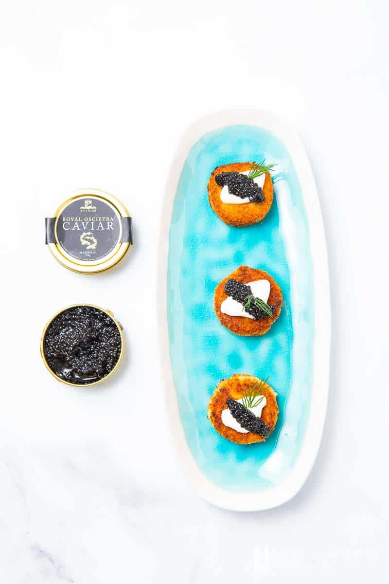 A plate of three salmon rissoles with a can of caviar 