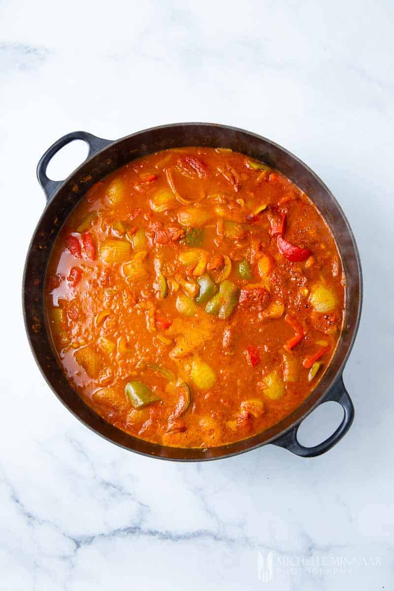 A stovetop pot full of curry sauce and vegetables