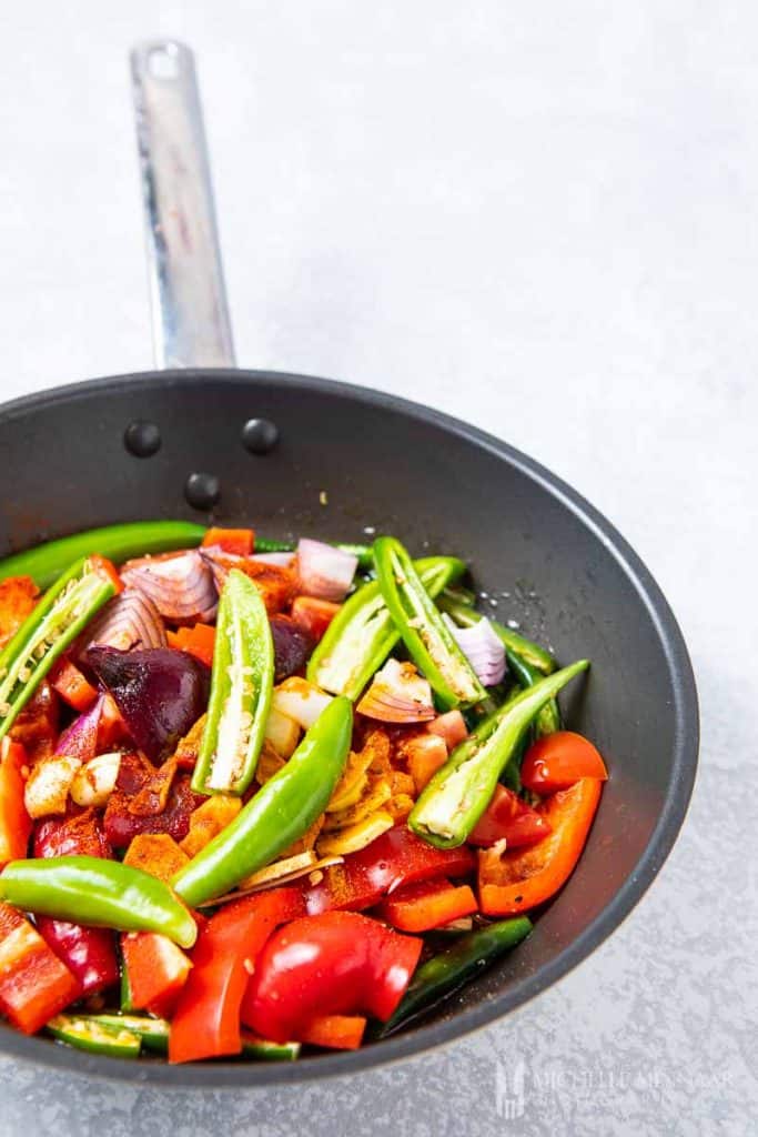 A close up of vegetables cooking in a saute pan 