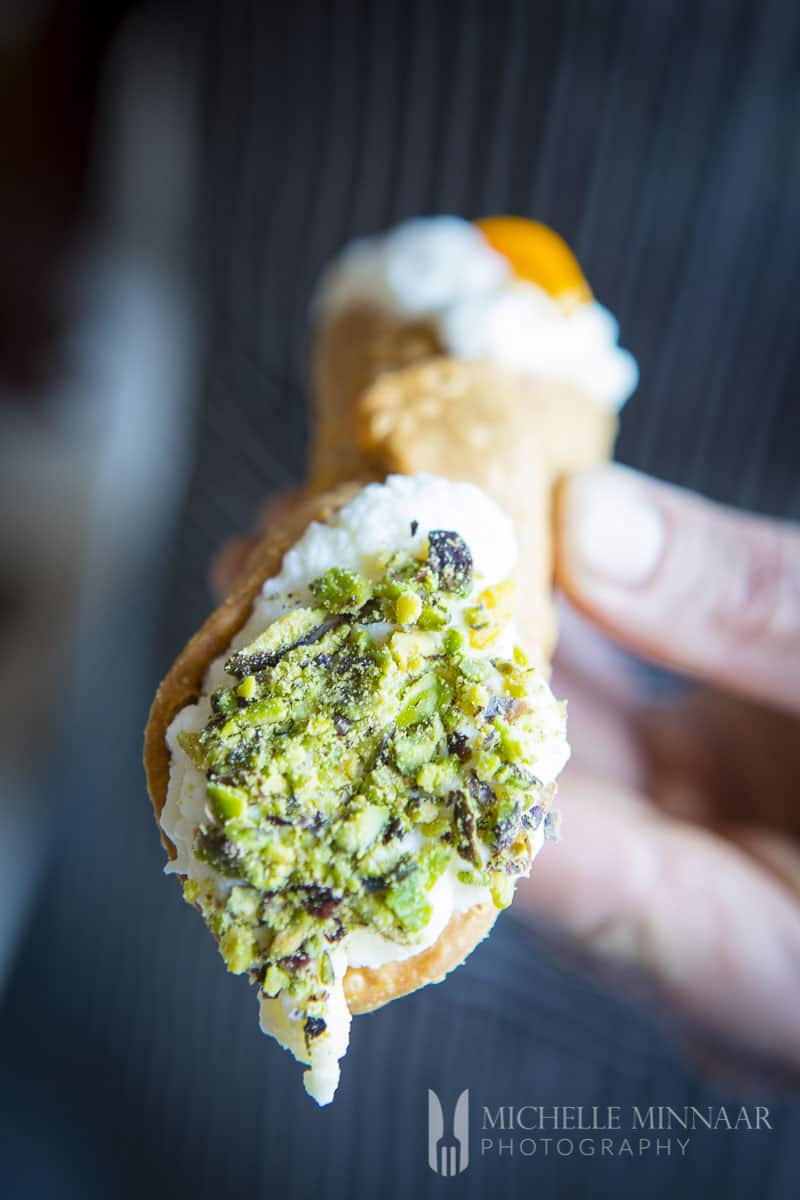 A cannoli with a pistachio tip 