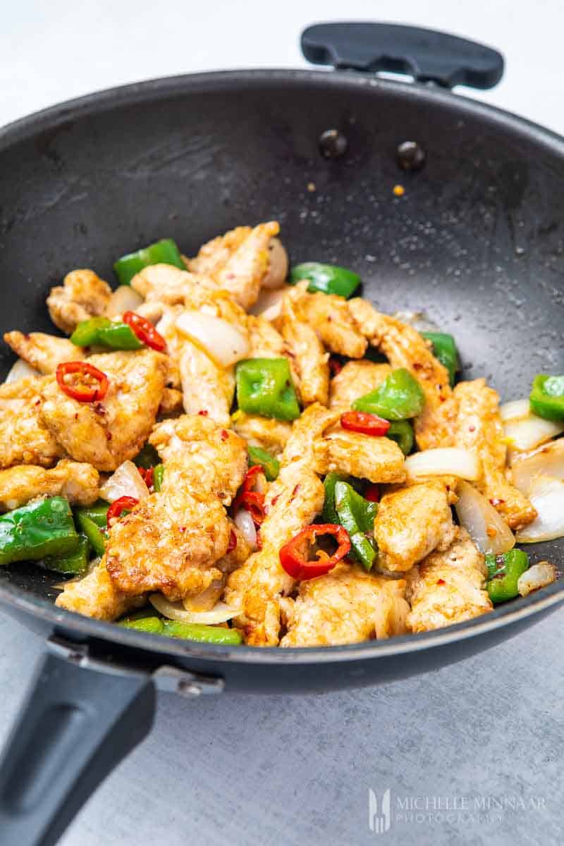 salt and chili chicken in a stir fry pan with vegetables