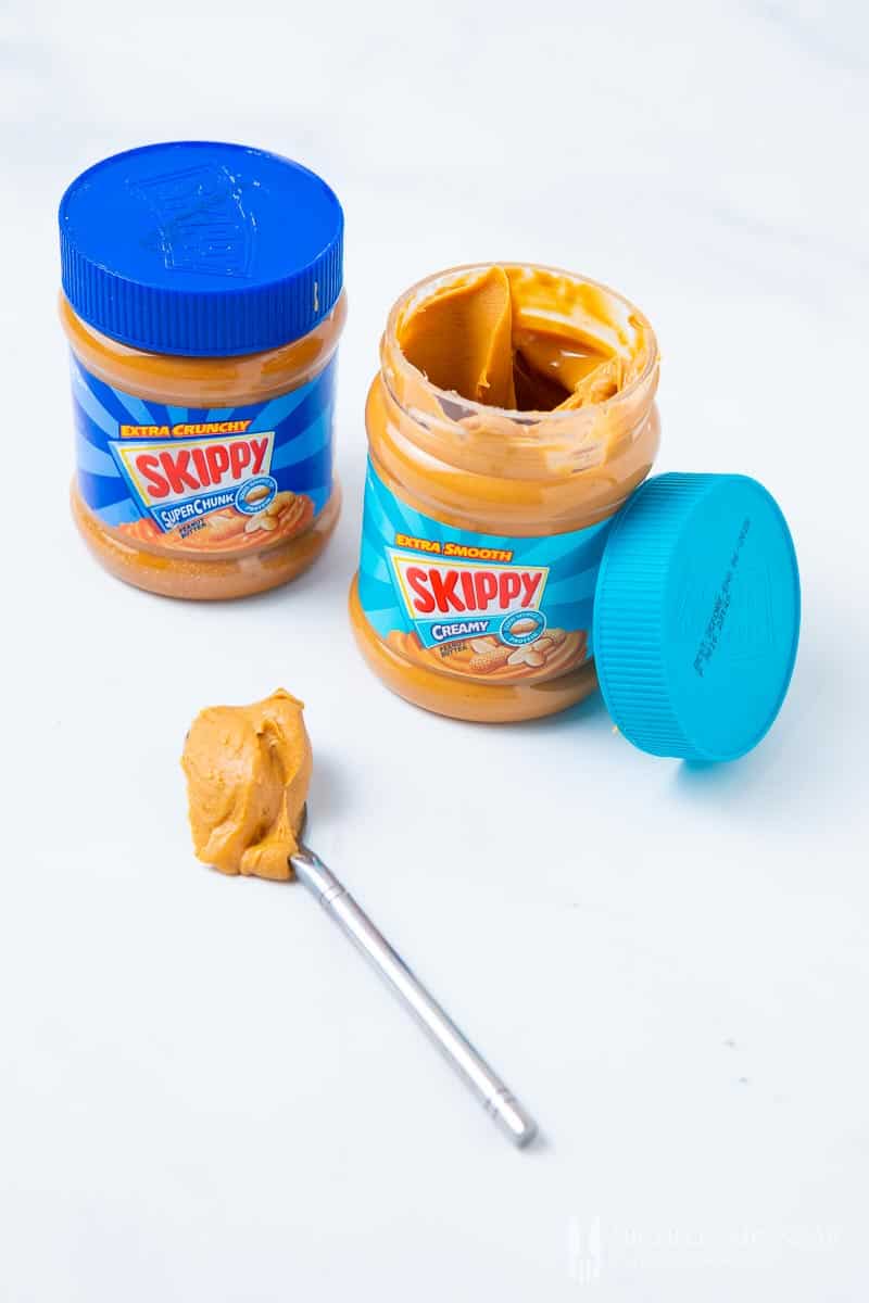 Two jars of Peanut Butter with a spoon 