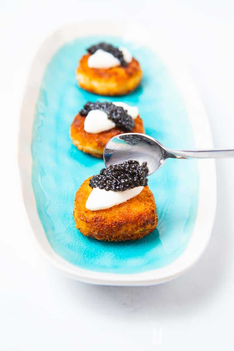 Caviar being spooned onto a salmon rissoles
