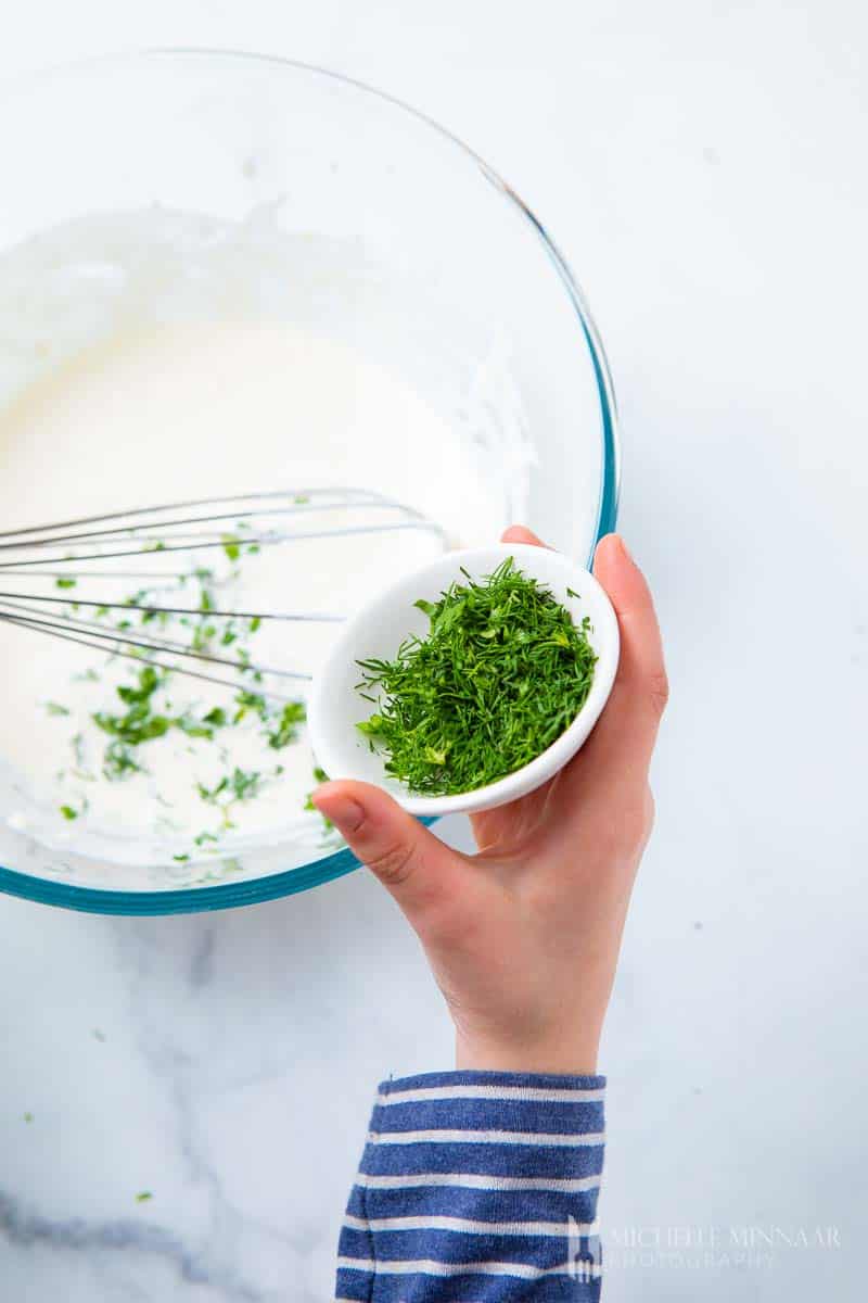 Putting herbs into a glass bowl 