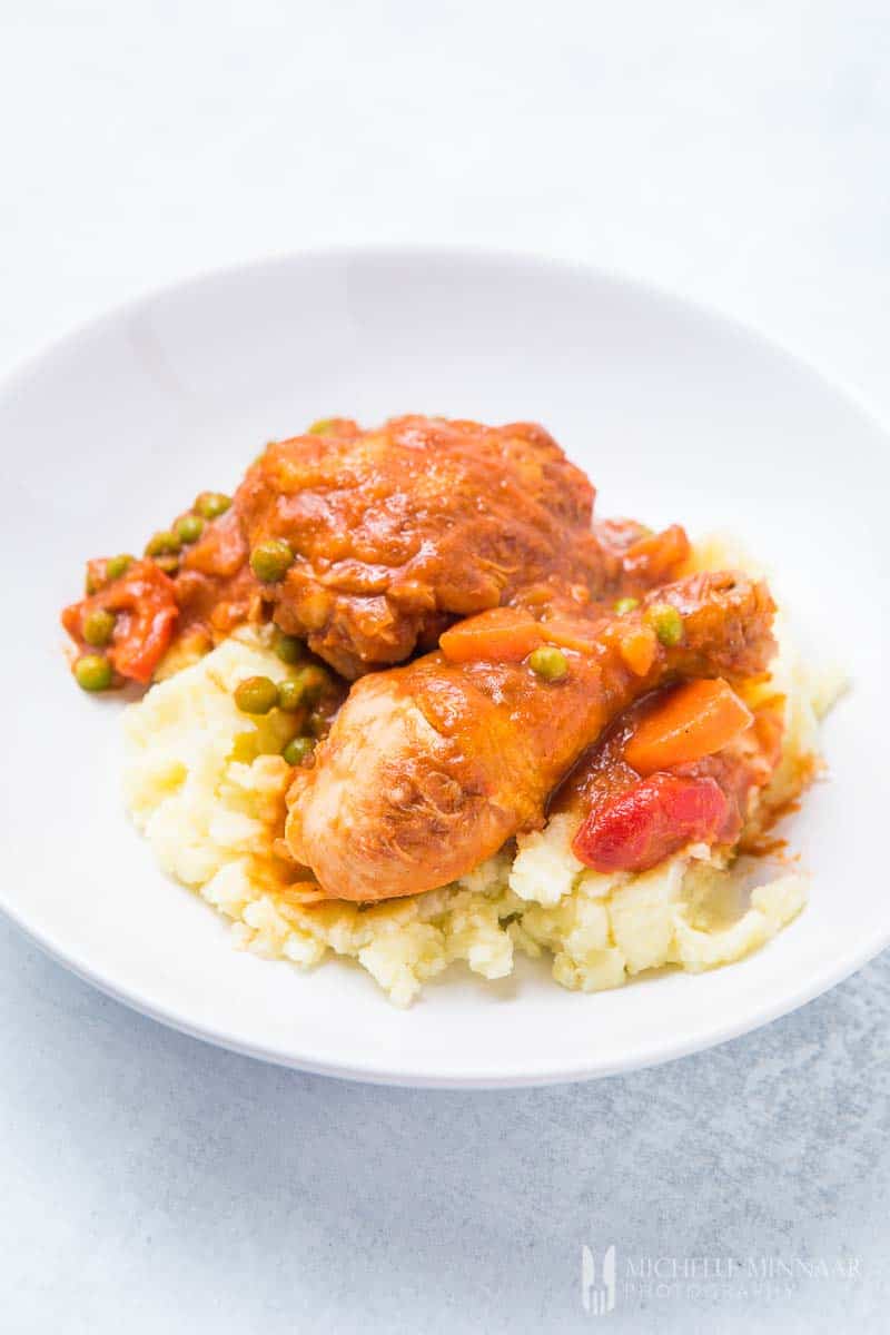 A plate of chicken caldereta on a bed of potatoes