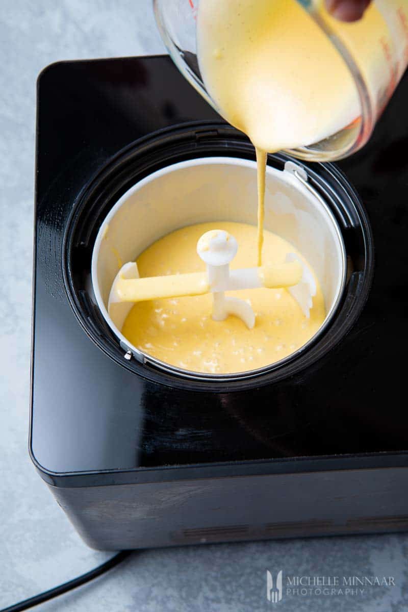 Yellow cream being poured into an ice cream maker