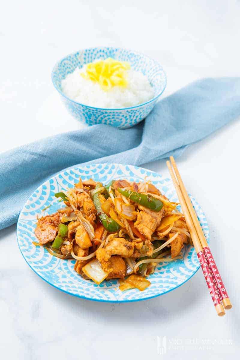 A plate of yasai itame, noodles and vegetables with a bowl of rice