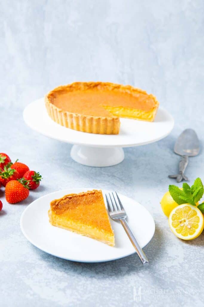 A yellow lemon chess pie with a slice on a plate