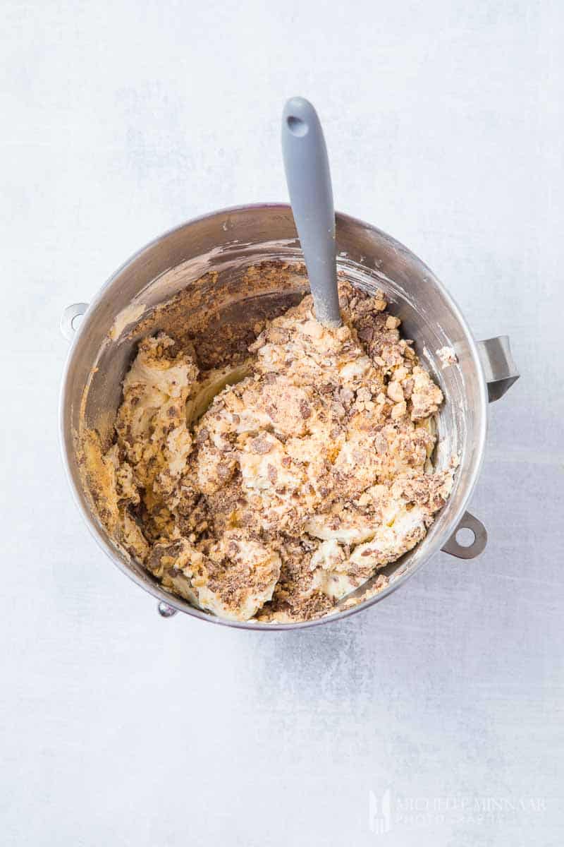 A bowl filled with cream cheese and crumbles being mixed