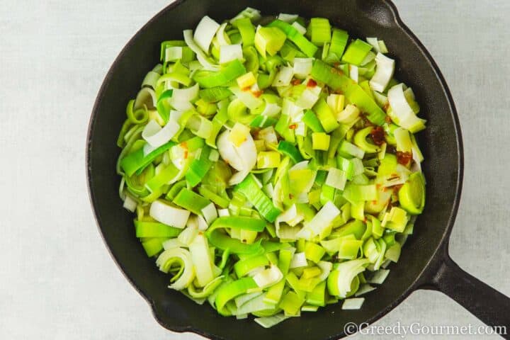 Chopped leeks with stock in a pan.