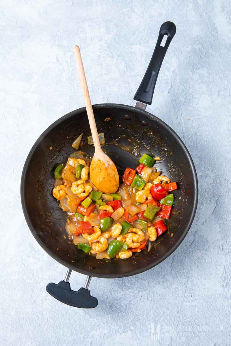 Shrimp and veggies being sauteed in a pan 