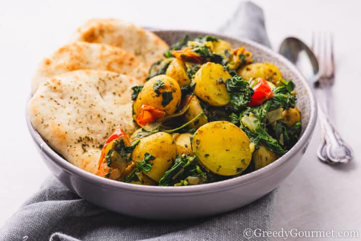 Saag Aloo served in a bowl with naan.