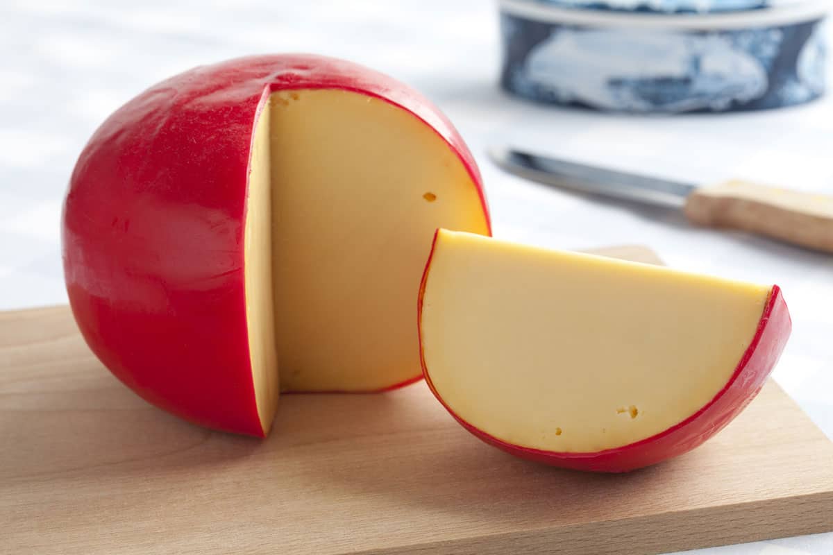 A round cheese block with a red rind.