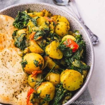 Saag Aloo served in a bowl with naan.