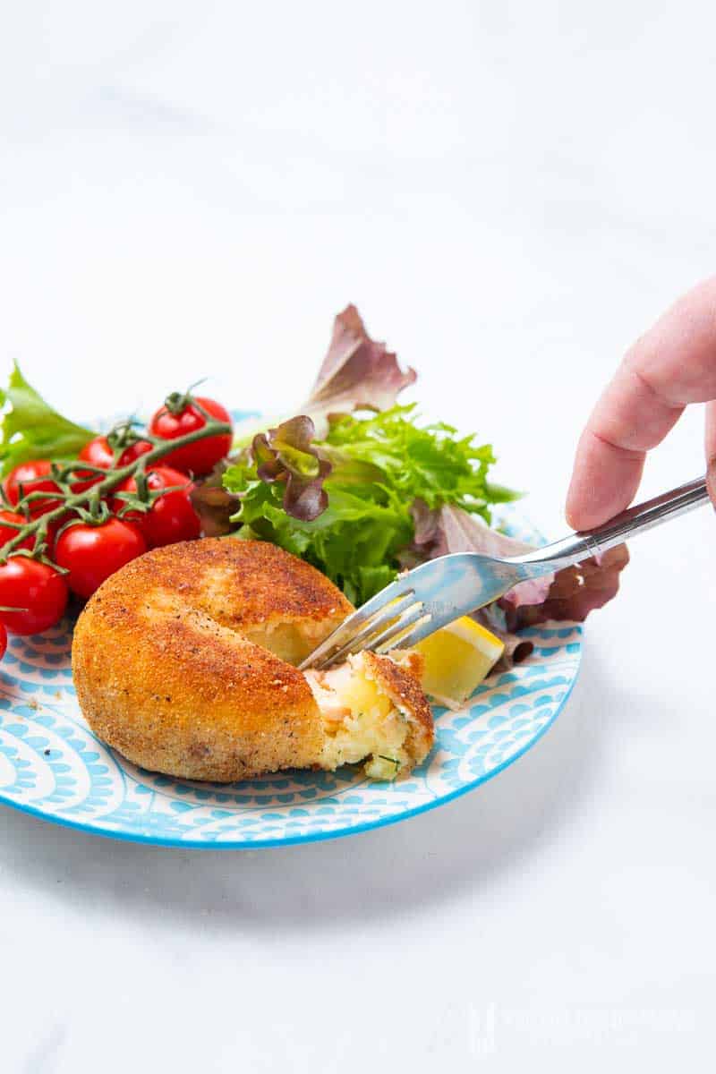 Eating salmon fishcake with a fork.