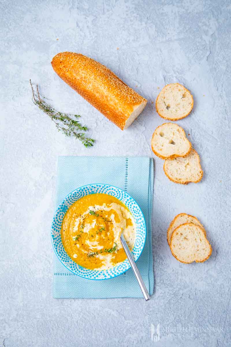 A bowl of carrot swede soup with a loaf of bread