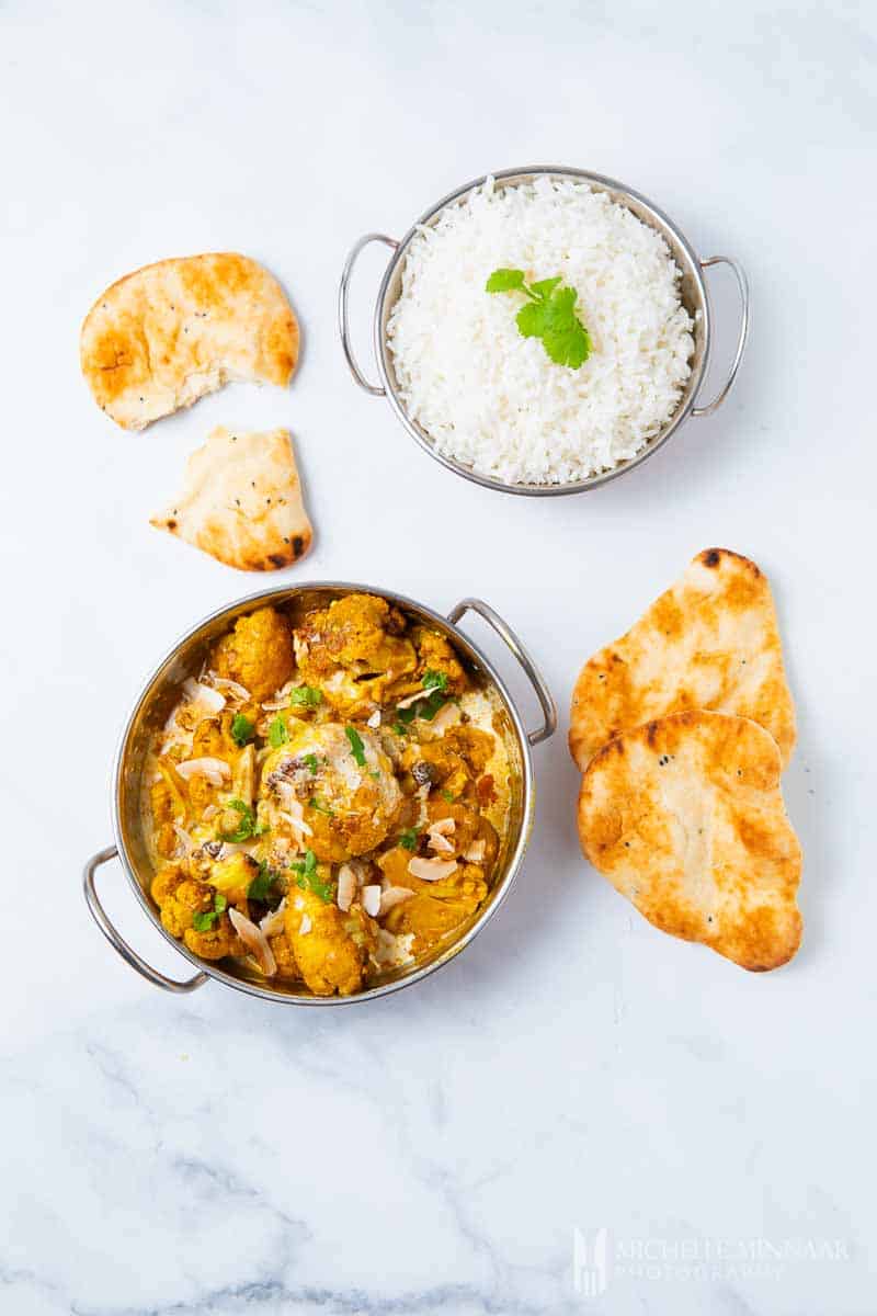 A bowl of cauliflower kurma with rice and naan