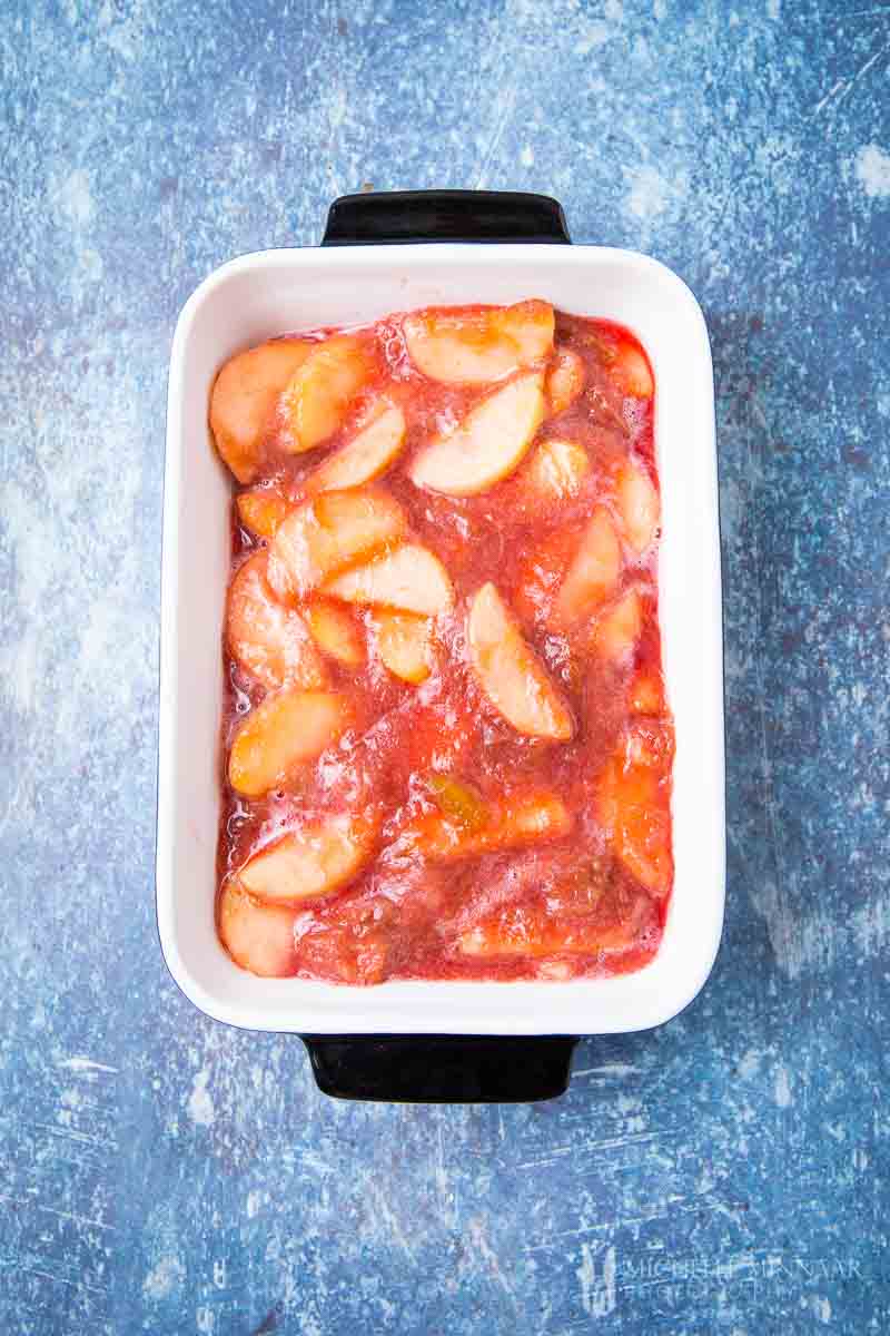 Apples in a white dish and red rhubarb sauce 