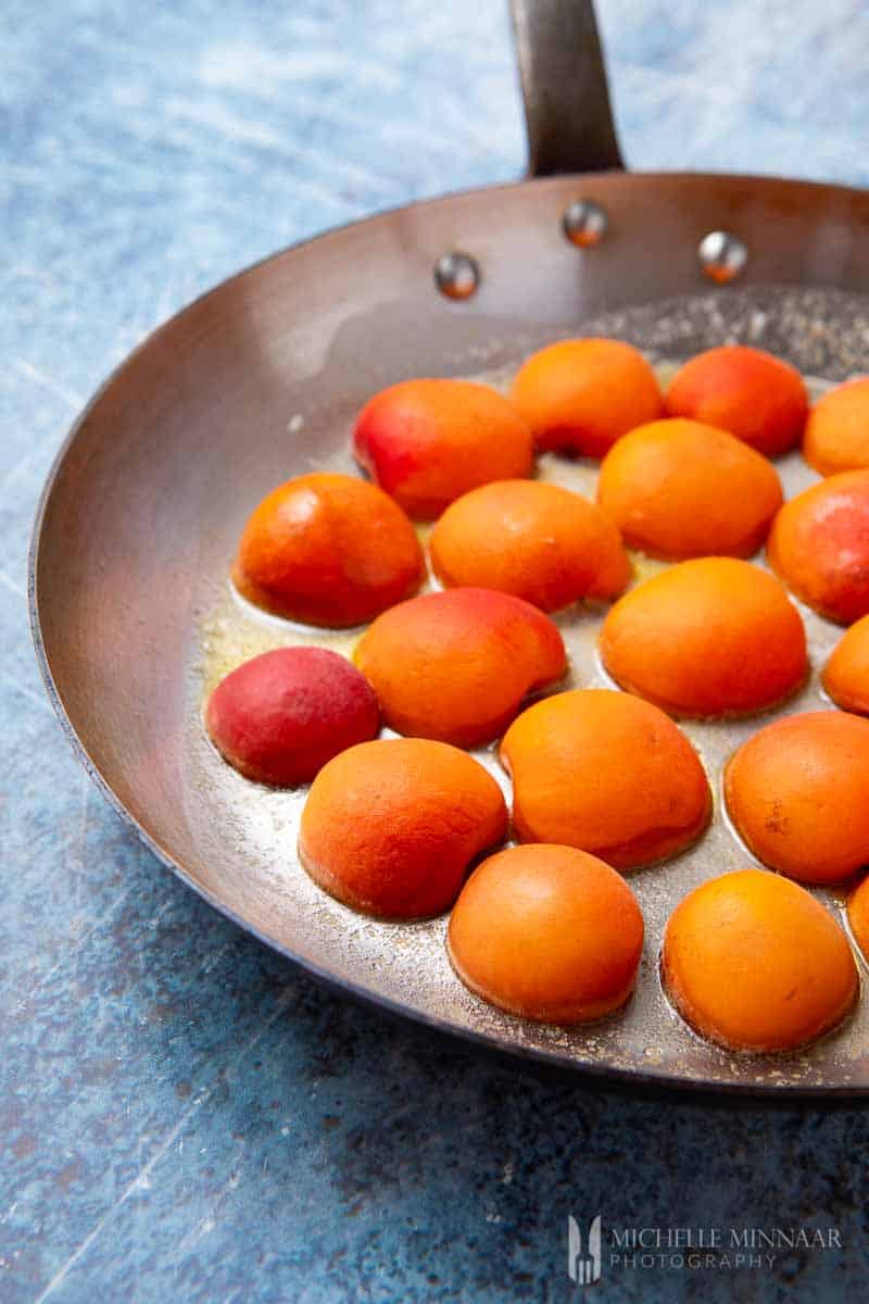 Orange apricots simmering in a pan 