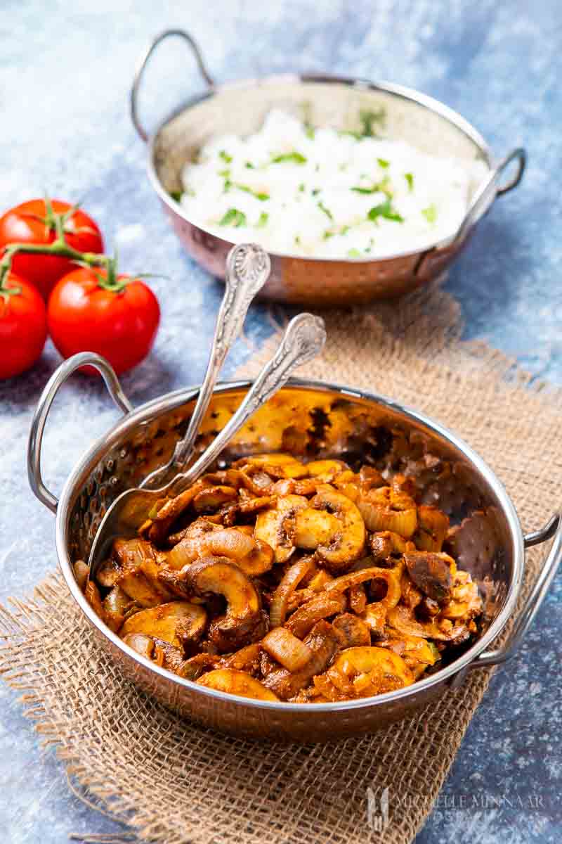 mushroom bhaji in a silver bowl with spoon and fork 