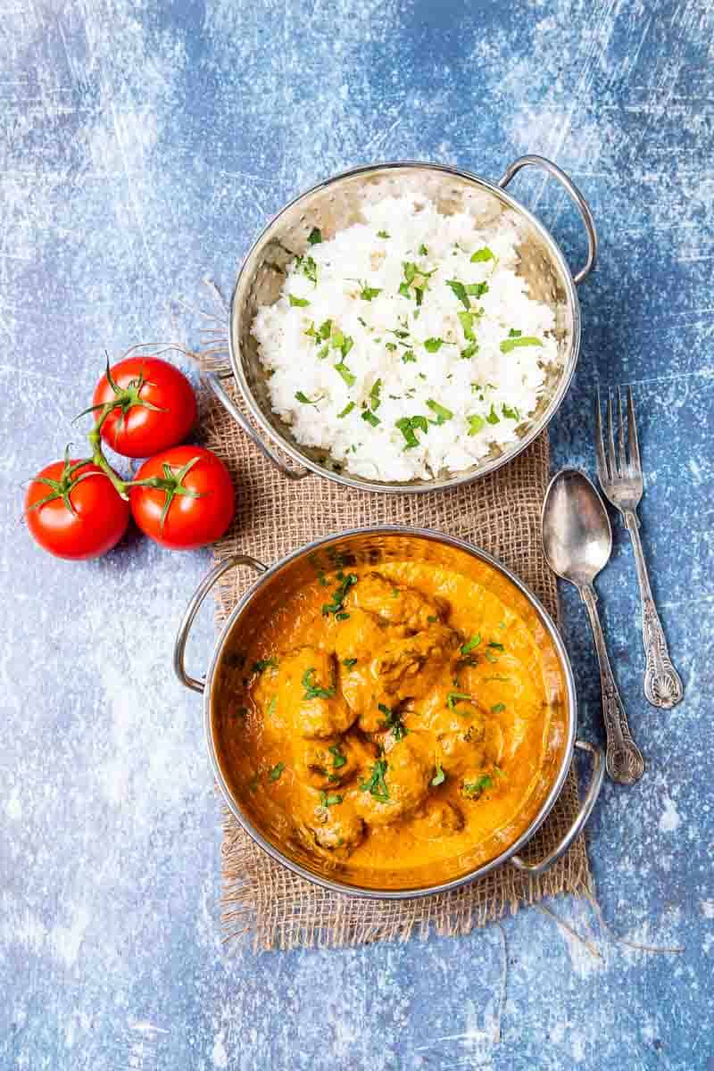 A bowl of lamb tikka masala and white rice 