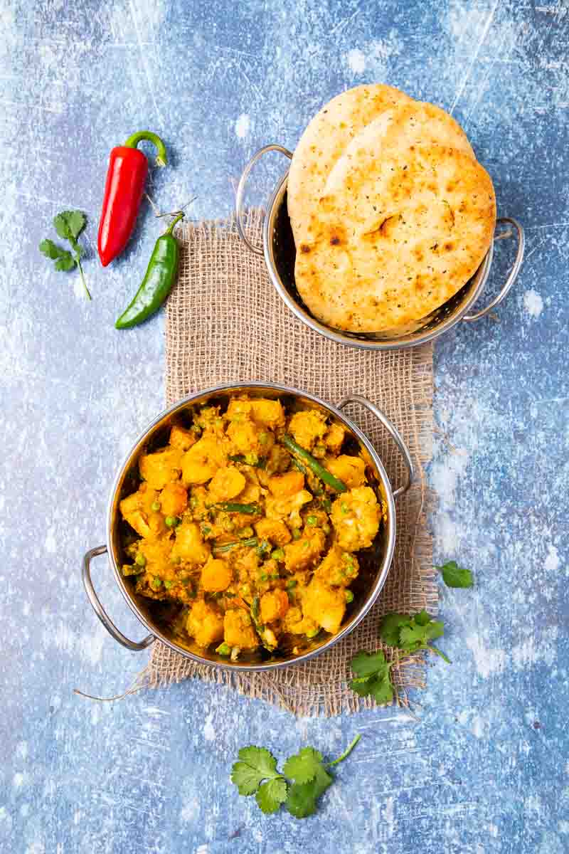 Freshly cooked mixed vegetable curry, naan and peppers