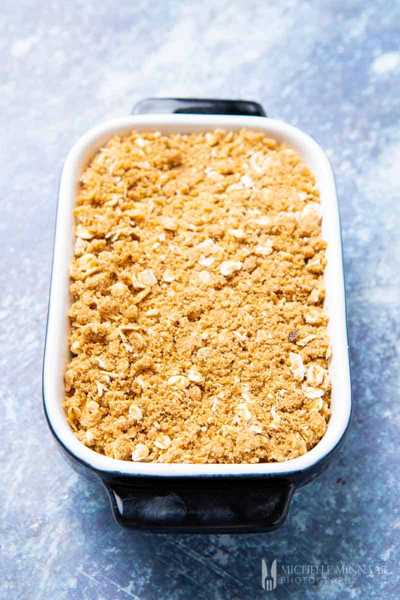 Crumbles on top of apples in a white dish